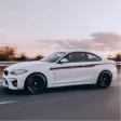 White sporty sedan driving fast on a road with blurred background and black wheels.