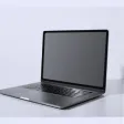 Silver laptop with blank screen on a white surface against a gray background.