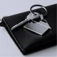 Two keys on a silver keyring with a blank rectangular metal keychain on a black wallet.