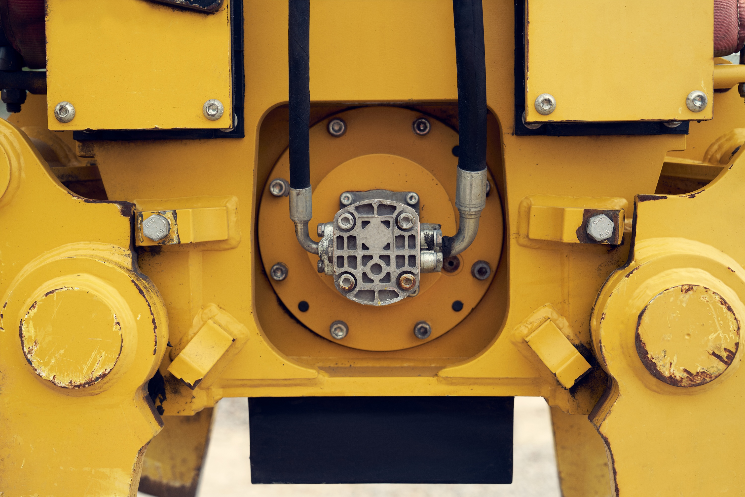 Close-up of a yellow industrial machine with metal pipes and bolts.
