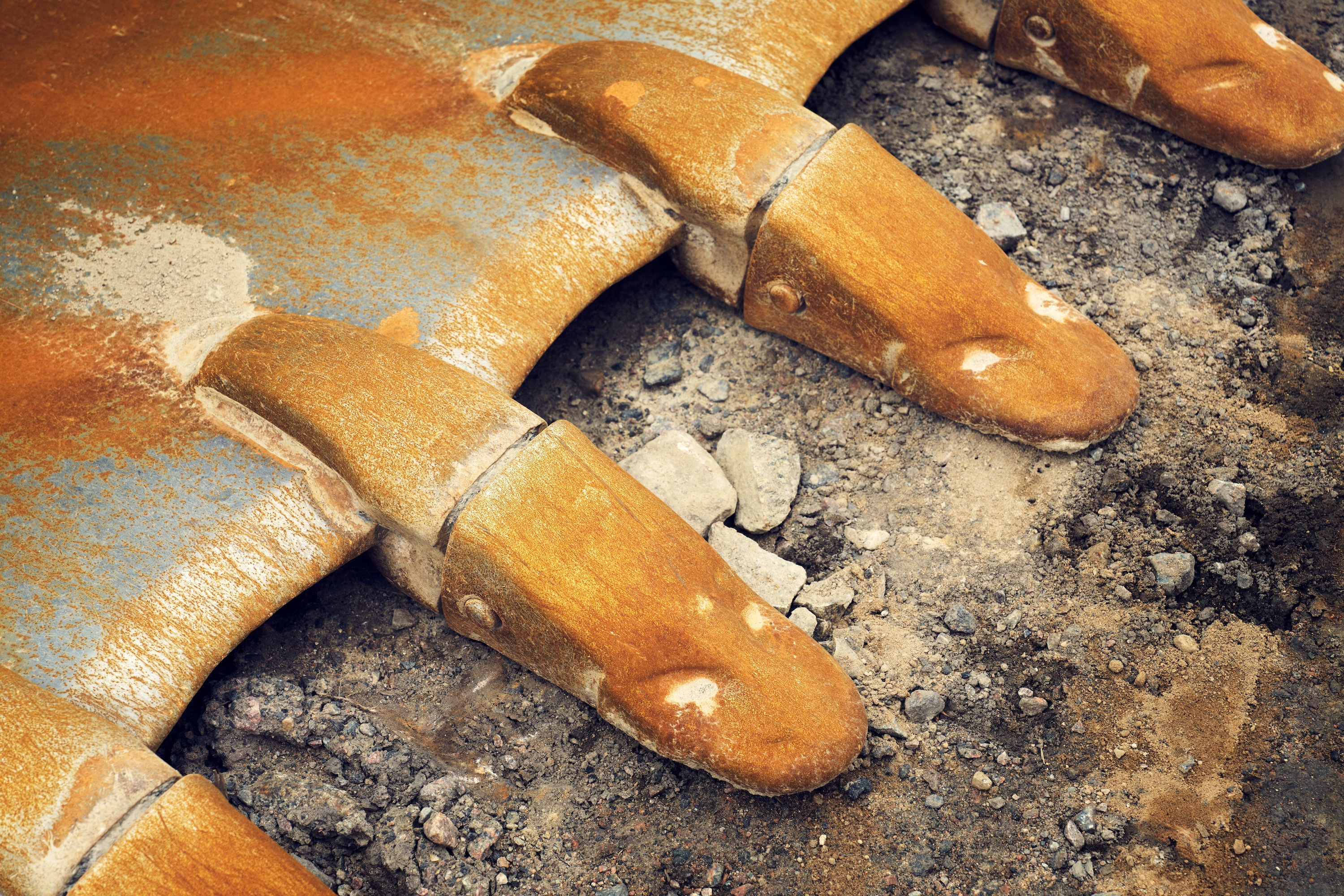 Close-up of an excavator digging into soil and rock.