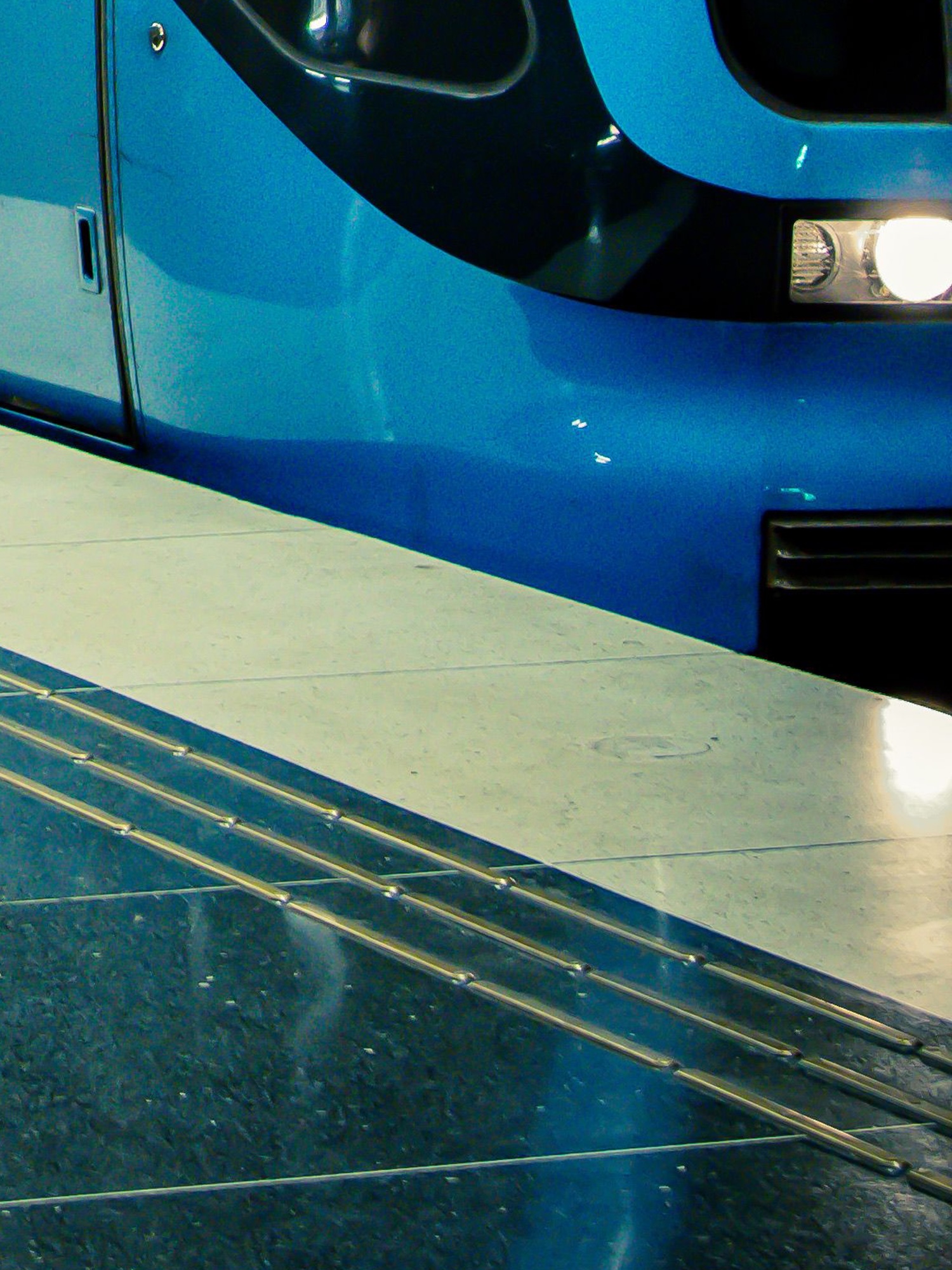 Close-up of blue subway car at platform edge.