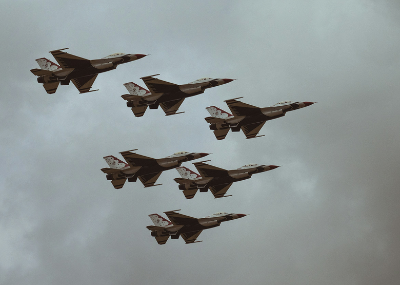 Six fighter jets flying in formation in a cloudy sky.