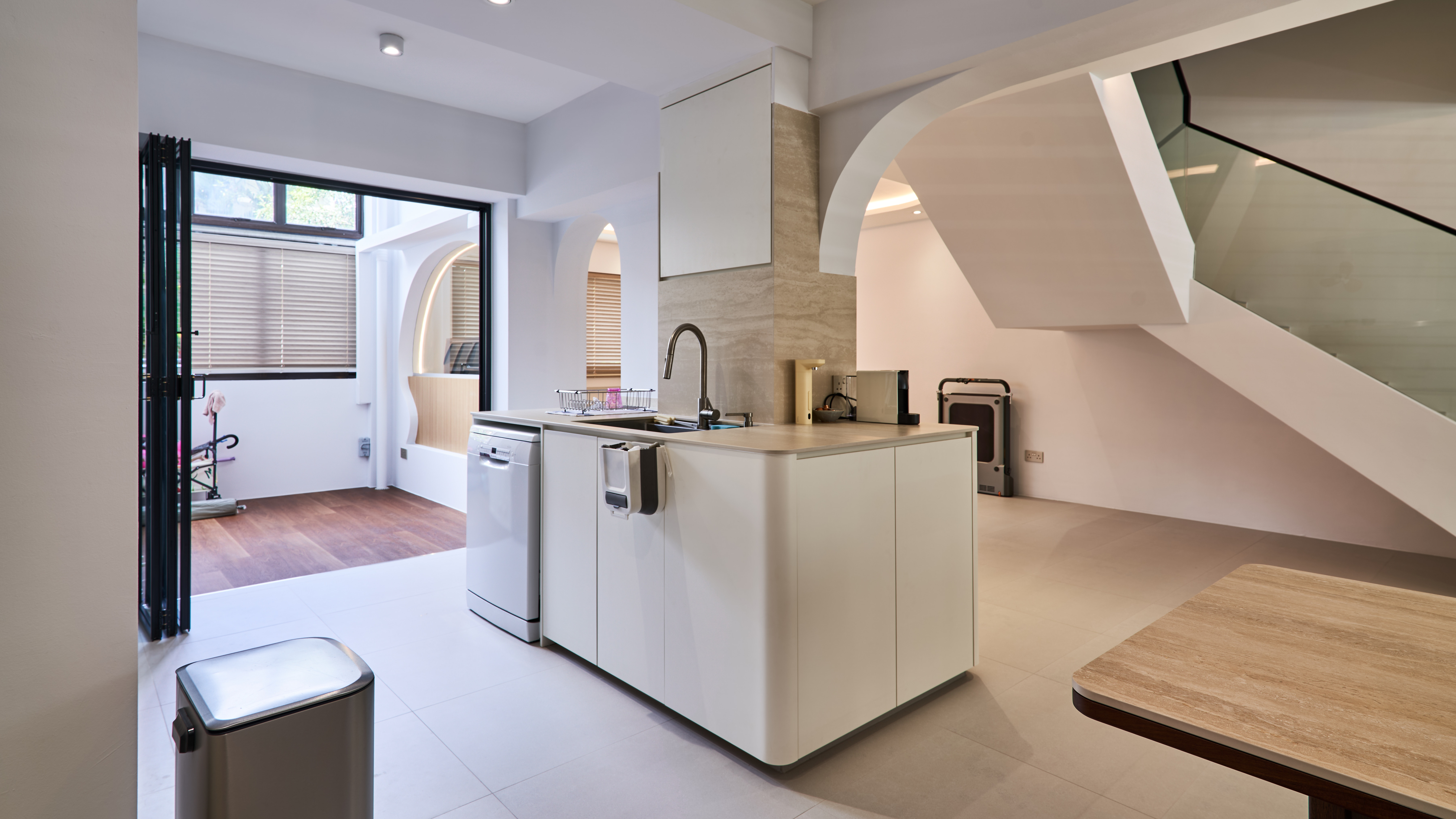 Bright white maisonette interior with curved arch details, open kitchen and staircase.