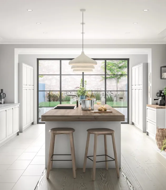 White kitchen with a wood island and garden-facing windows.