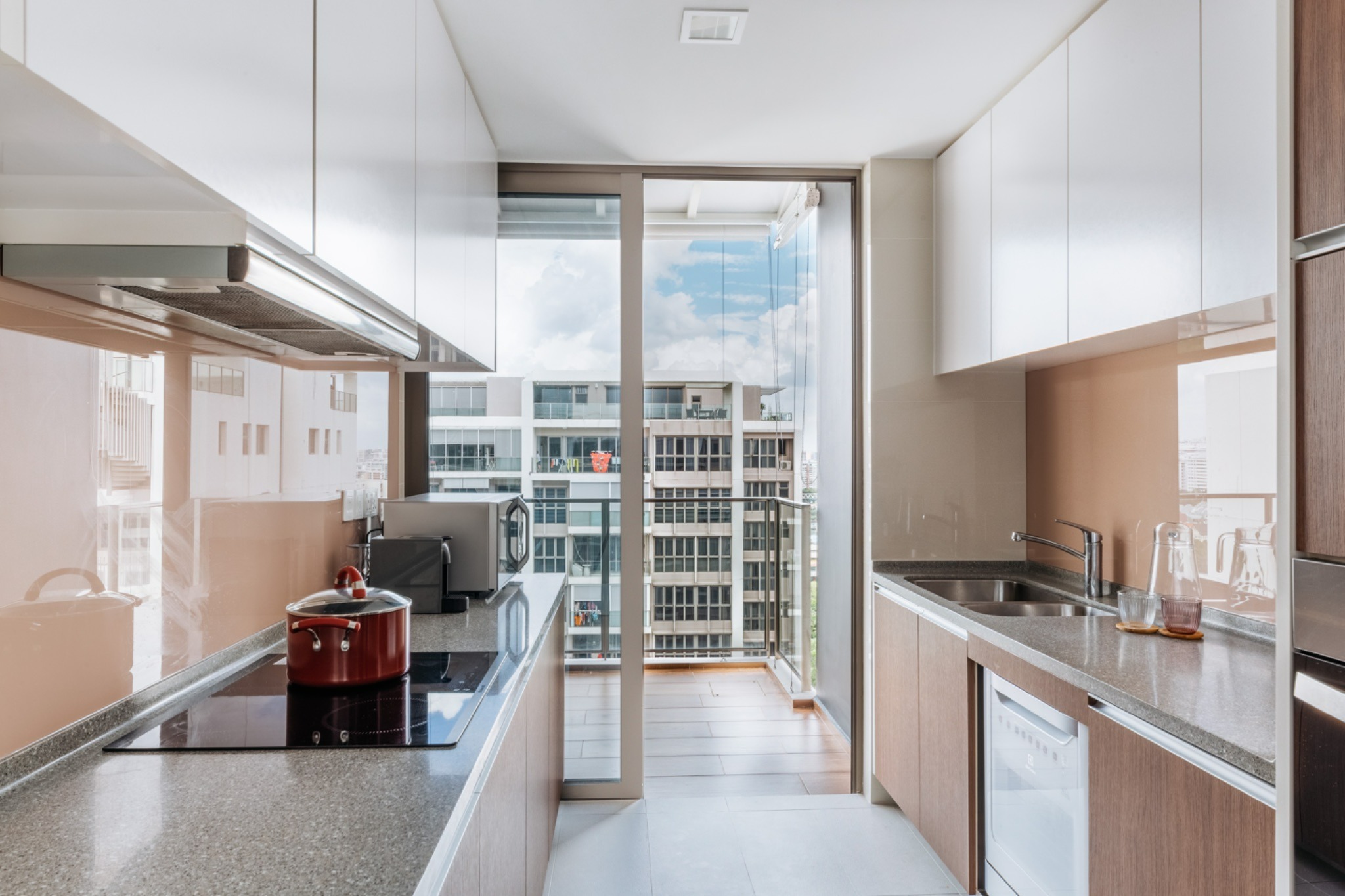 Narrow modern kitchen with white upper cabinets, wood-finish lower cabinets and grey countertops.