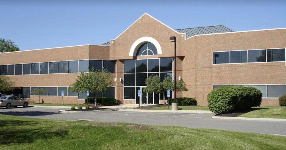 Exterior photo of a two-story brick medical office building with an arched glass entrance and accessible parking