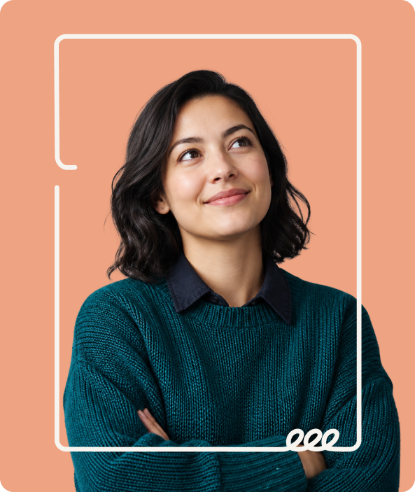 Young woman with dark hair in a teal sweater looking up and smiling against a peach background.