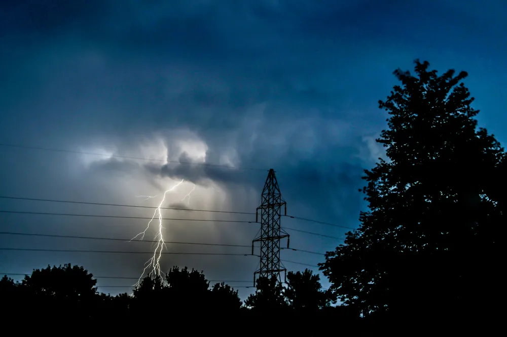Lightning over power lines at night, GridProtect power outage coverage