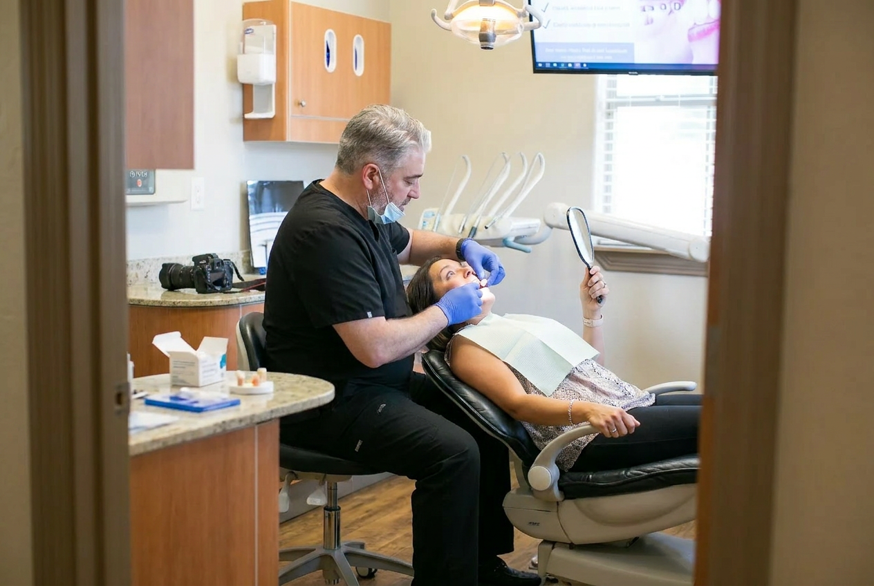 Dentist explaining a dental implant model to a seated patient