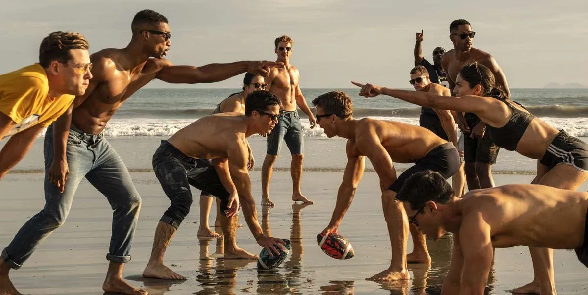 Beach football scene from Top Gun depicting people playing without shirts