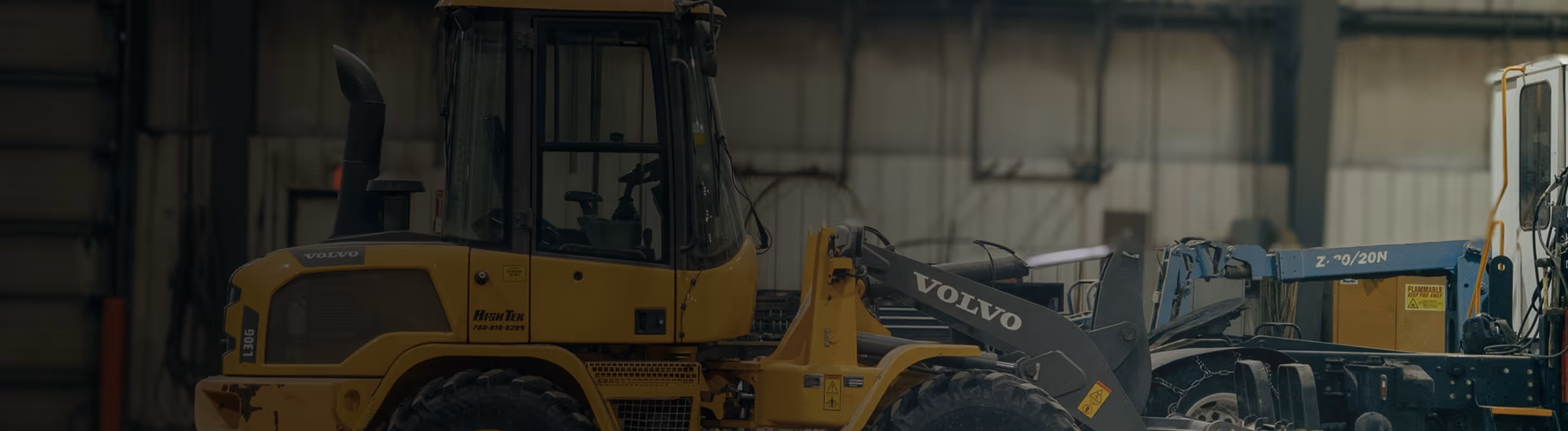 Yellow Volvo construction loader inside an industrial warehouse.