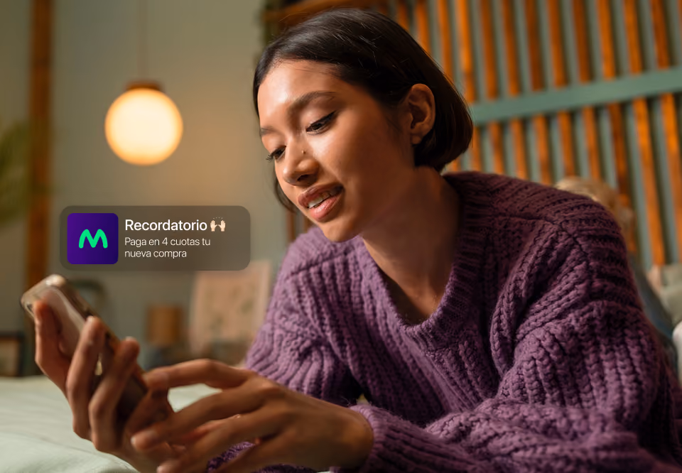 Young woman in purple sweater using a smartphone with a purchase reminder notification on screen.