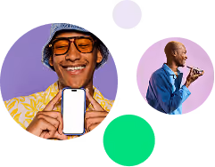 Smiling man in yellow shirt and hat holding a phone and another man speaking into a microphone.