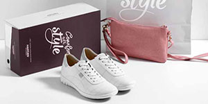 Weiße Komfortschuhe vor einem Schuhkarton und einer rosa Handtasche