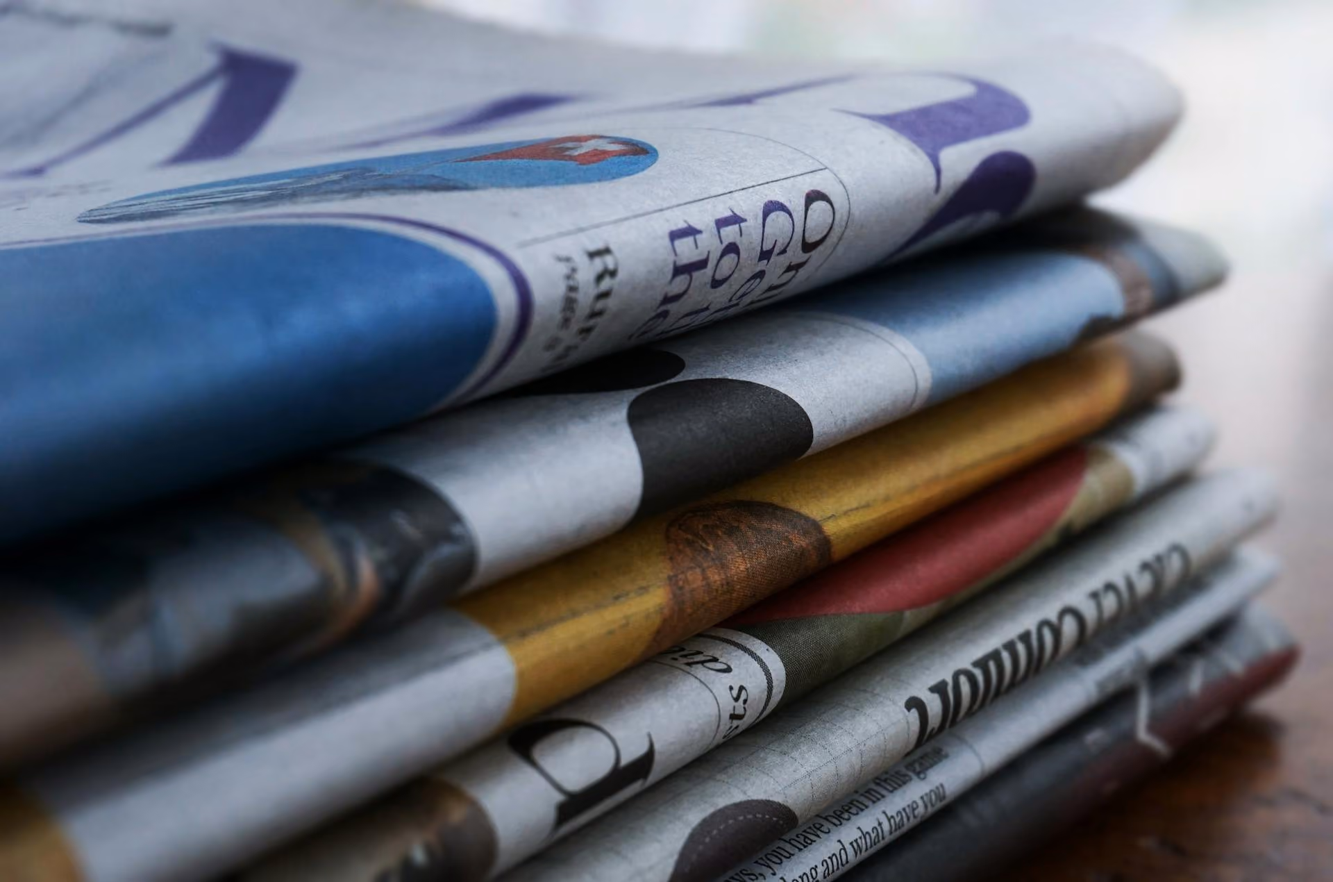 Close-up of a stack of folded newspapers on a wooden surface.