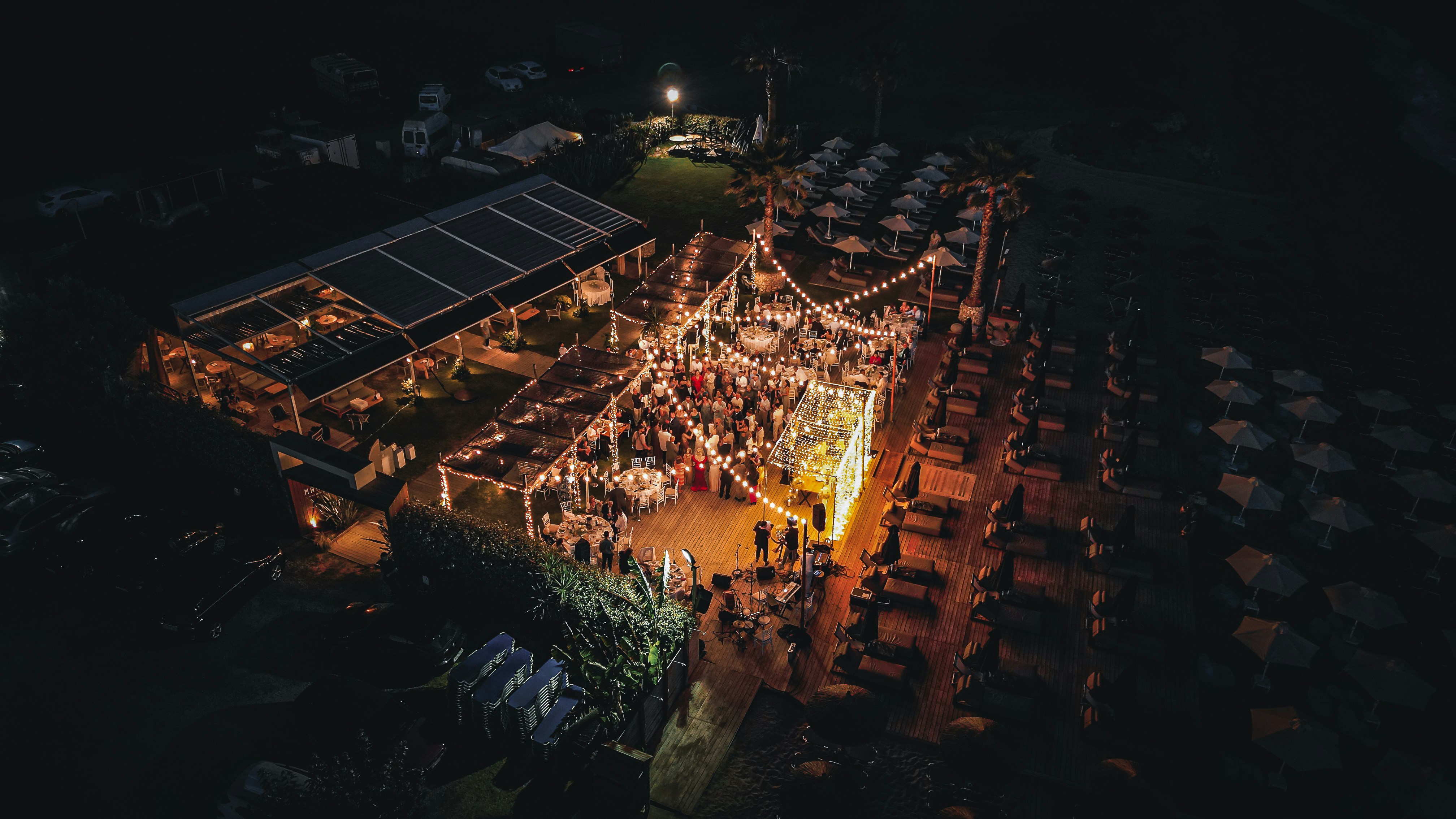 Ein Konzert bei Nacht aus der Vogelperspektive. Lichterketten sorgen für eine gemütliche Stimmung. Menschen stehen versammelt.