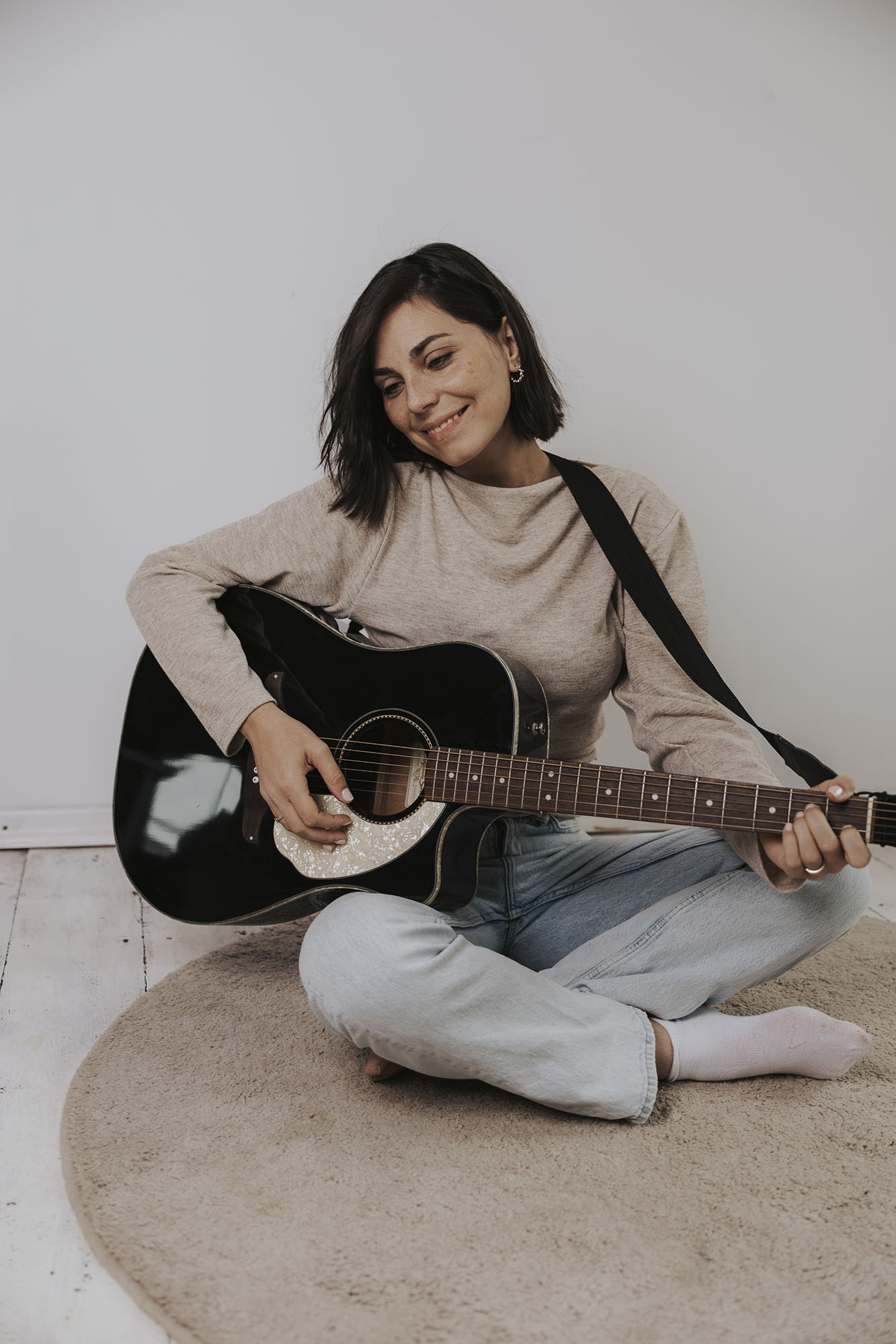 Musikpädagogin spielt Gitarre mit entspannter und zufriedener Haltung.