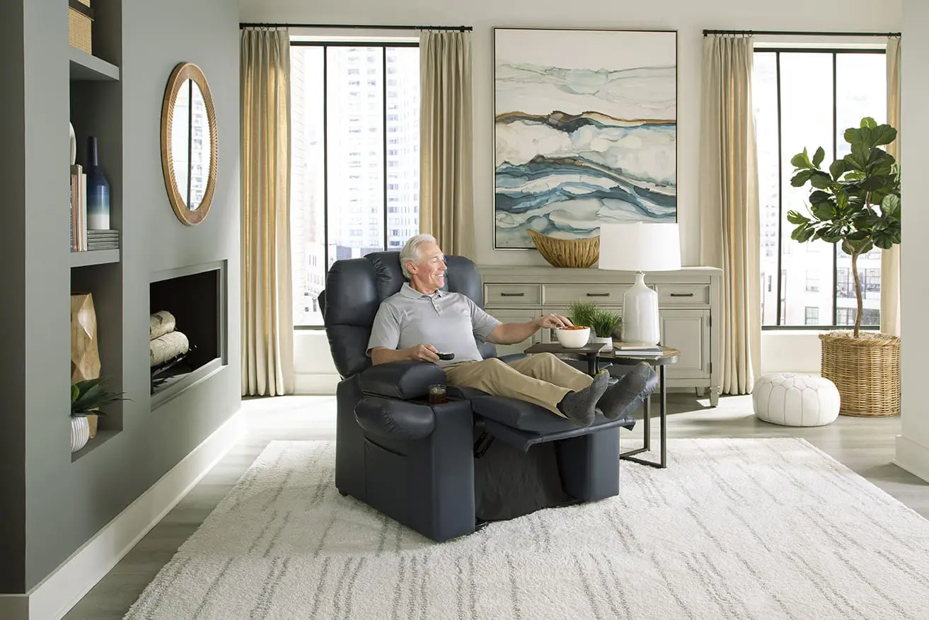 Older man relaxing in a black recliner chair in a bright living room with modern decor.