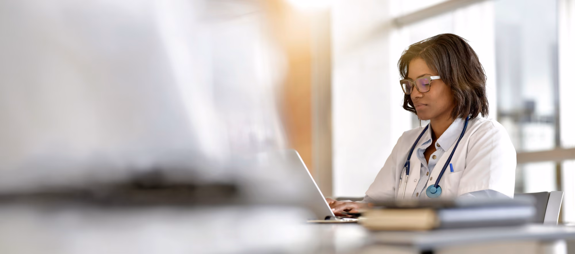 Health care provider in a white coat working at a laptop