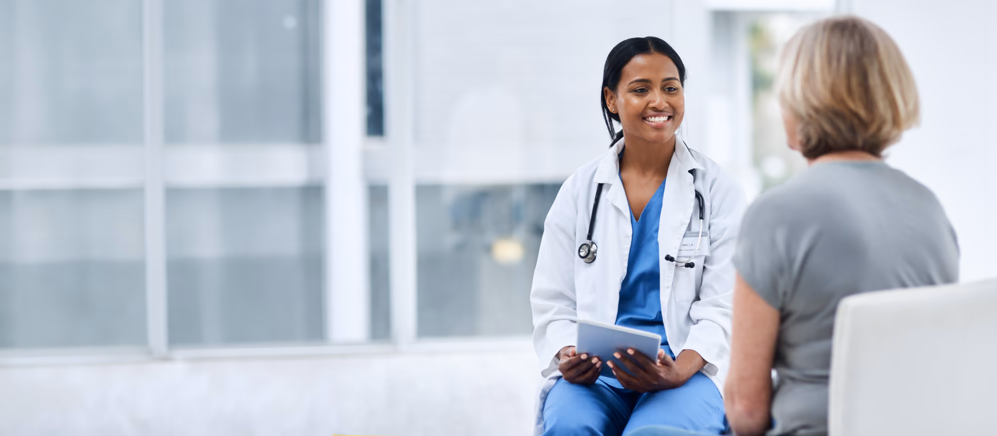 Doctor in a white coat smiling while talking with a woman in a clinic.