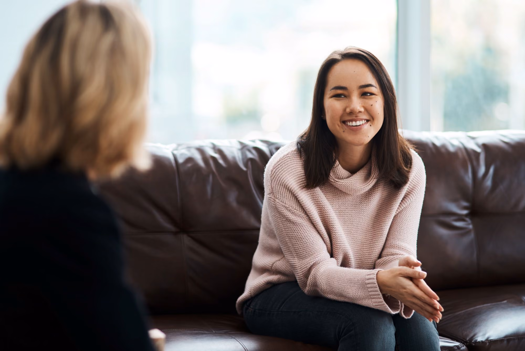 Woman sitting on a couch smiling during a conversation