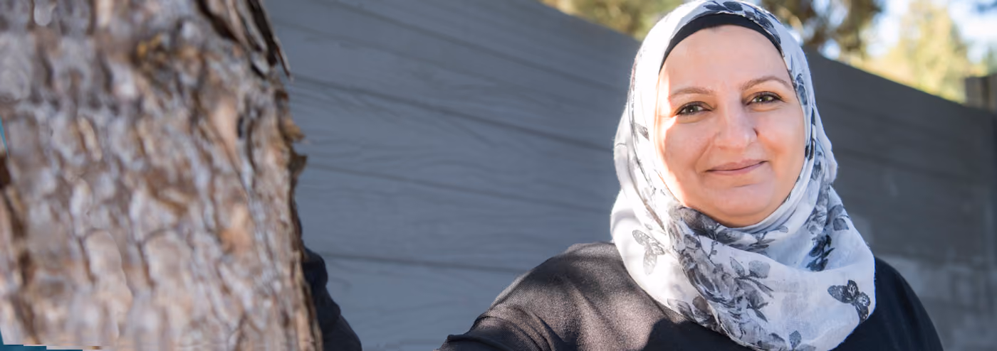 Woman wearing a patterned hijab, smiling.
