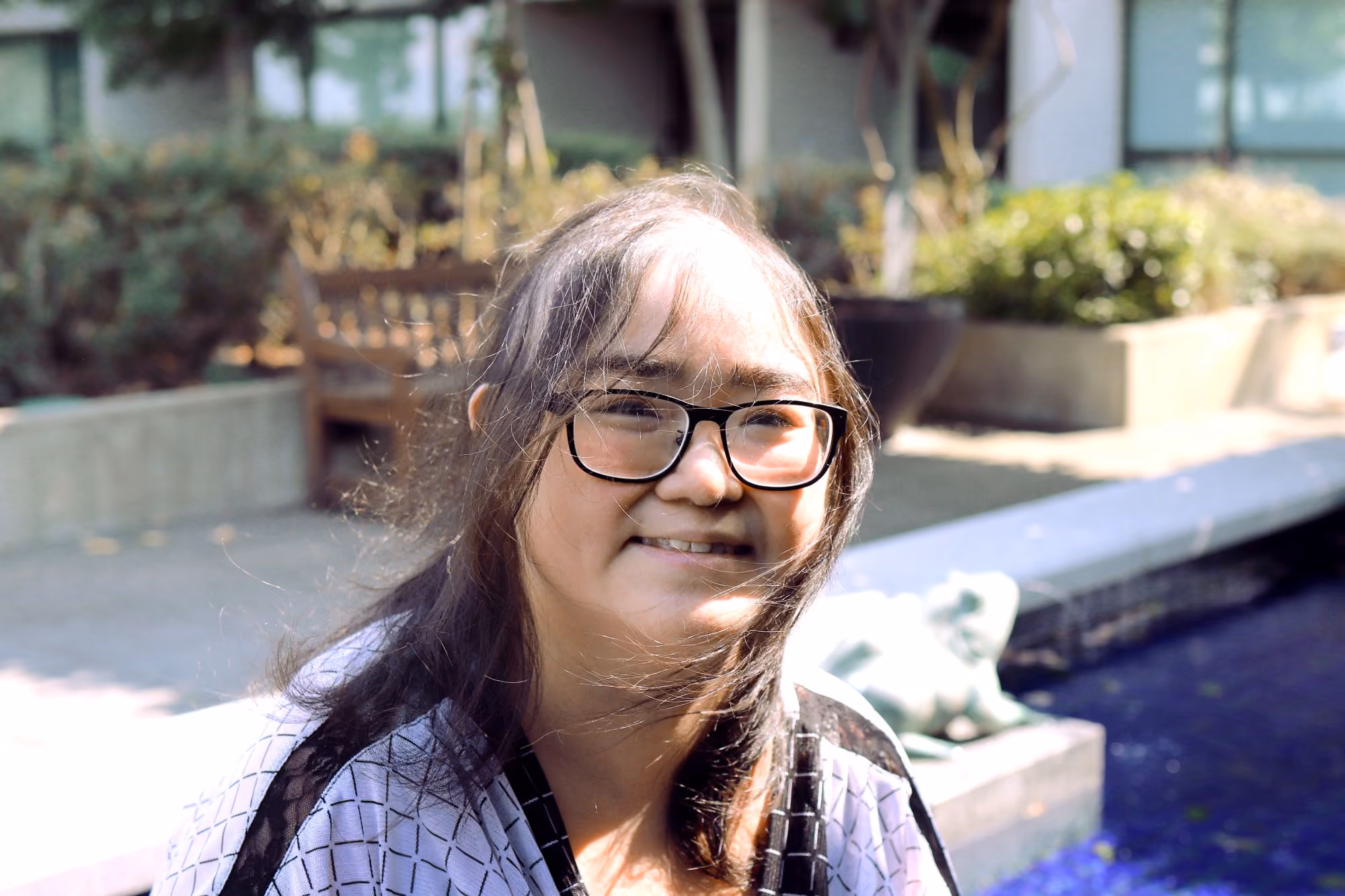 Young woman with glasses smiling outdoors.