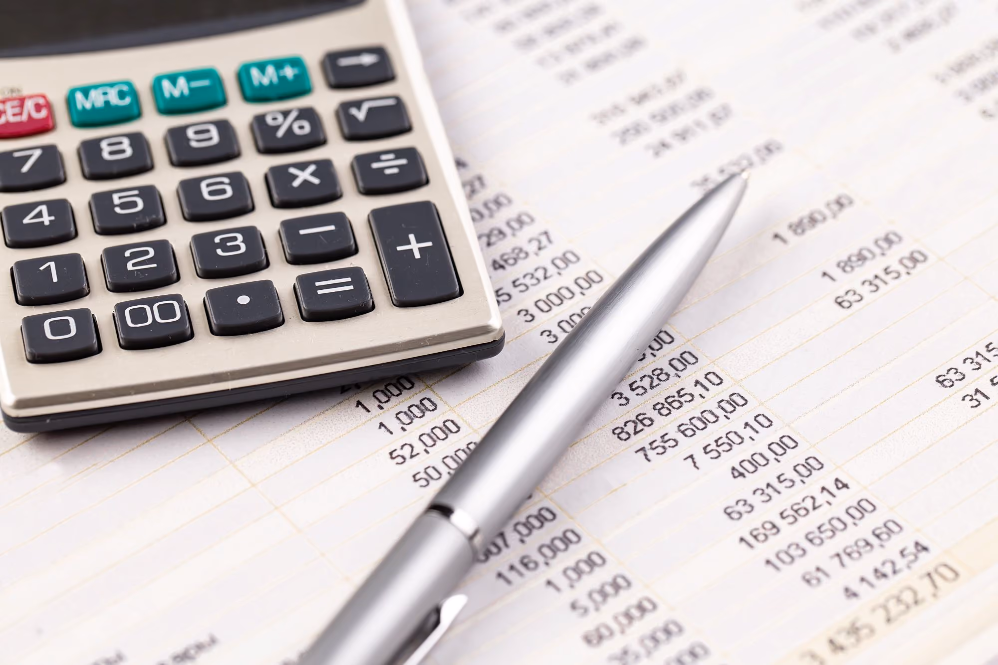 Calculator and pen resting on a printed financial statement.