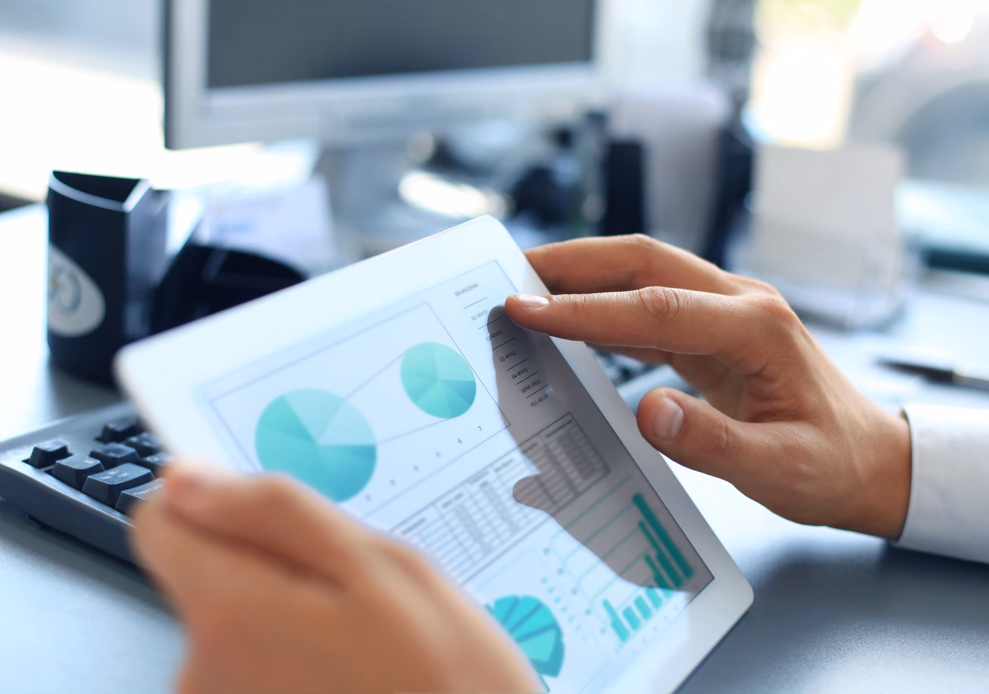 Hands holding a tablet showing charts and graphs.