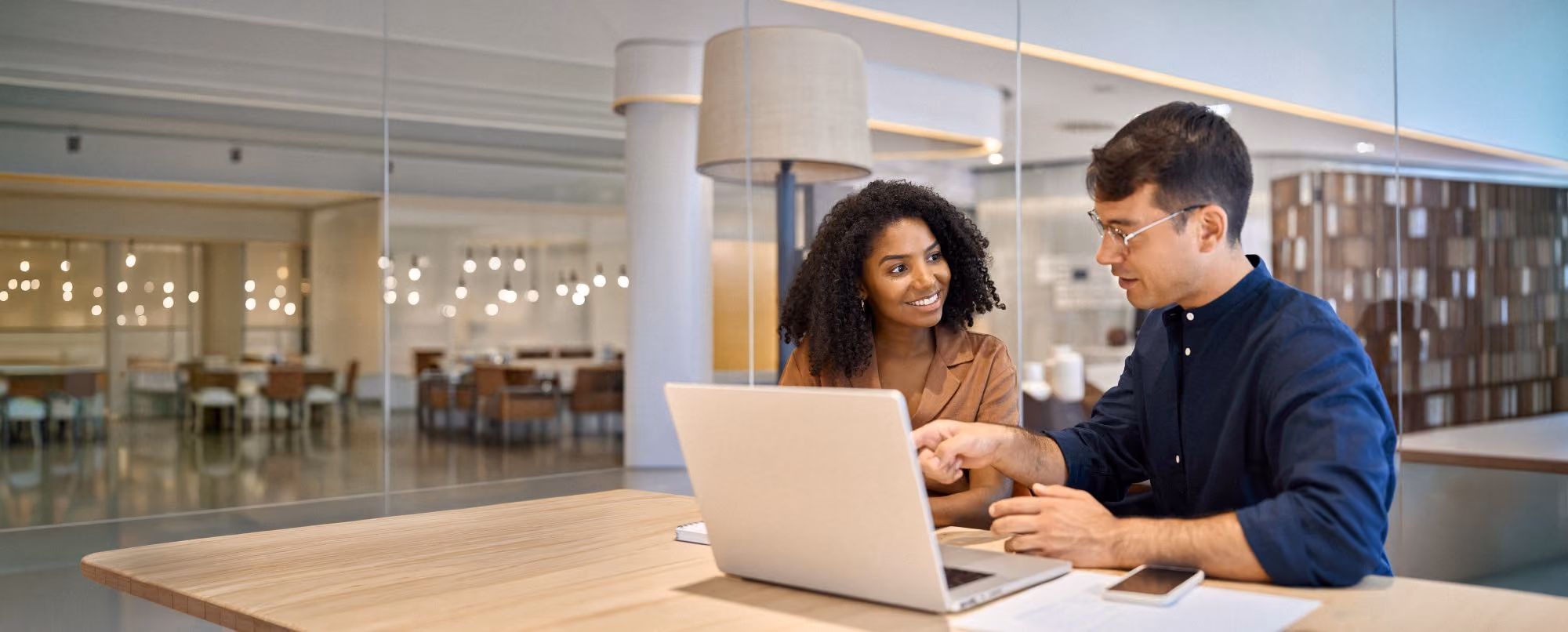 Two people looking at a laptop together in an office.