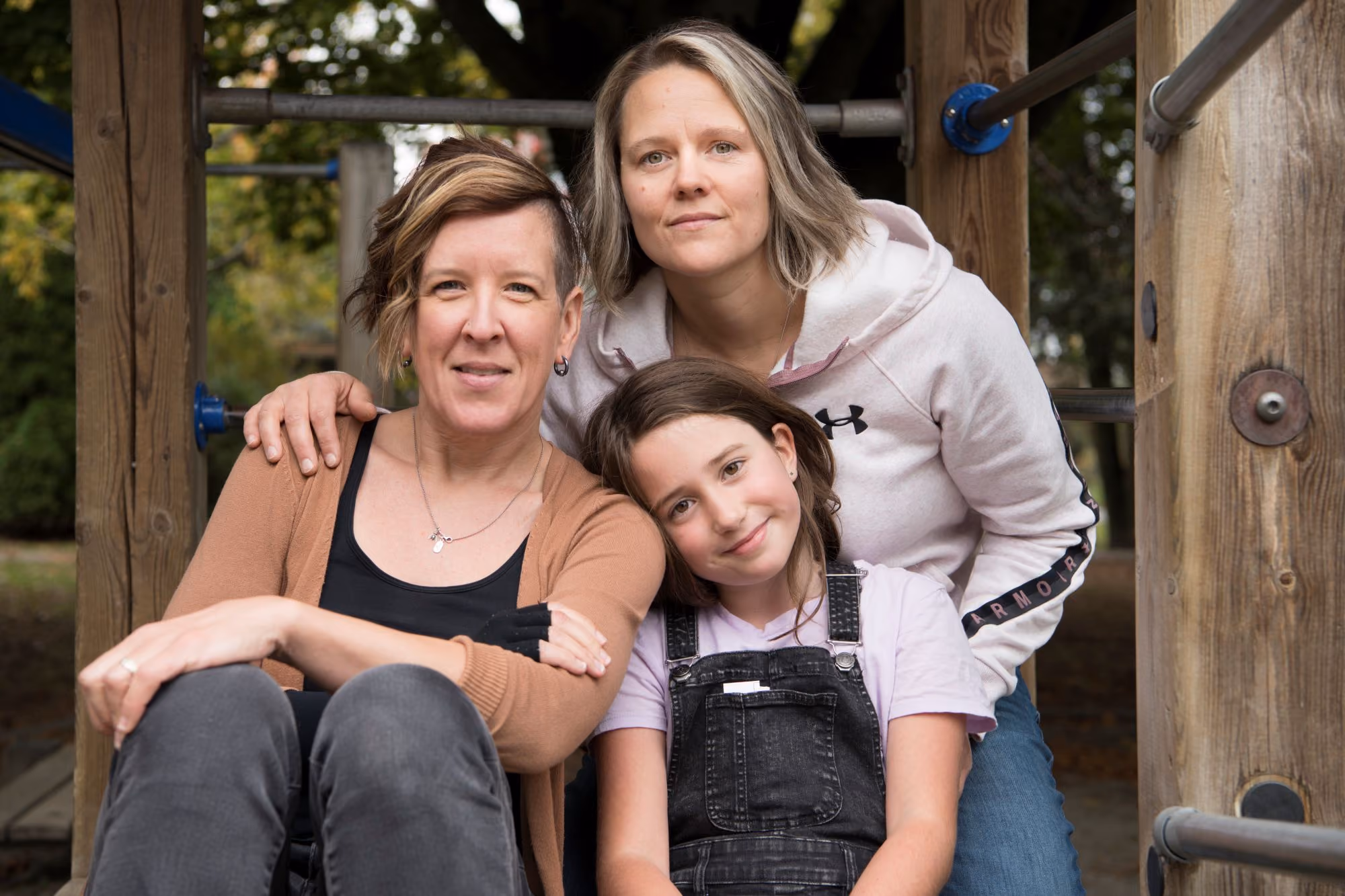 Two women and a child sitting close together on a playground structure.