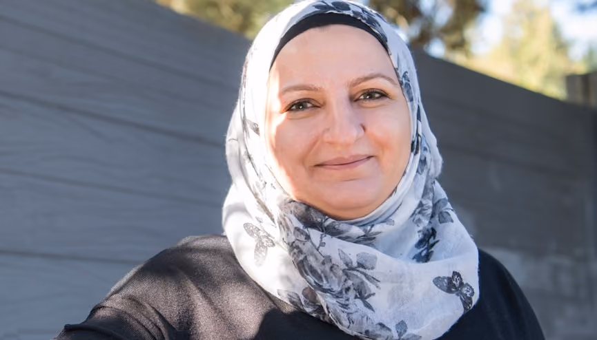 Woman wearing a patterned hijab, smiling.