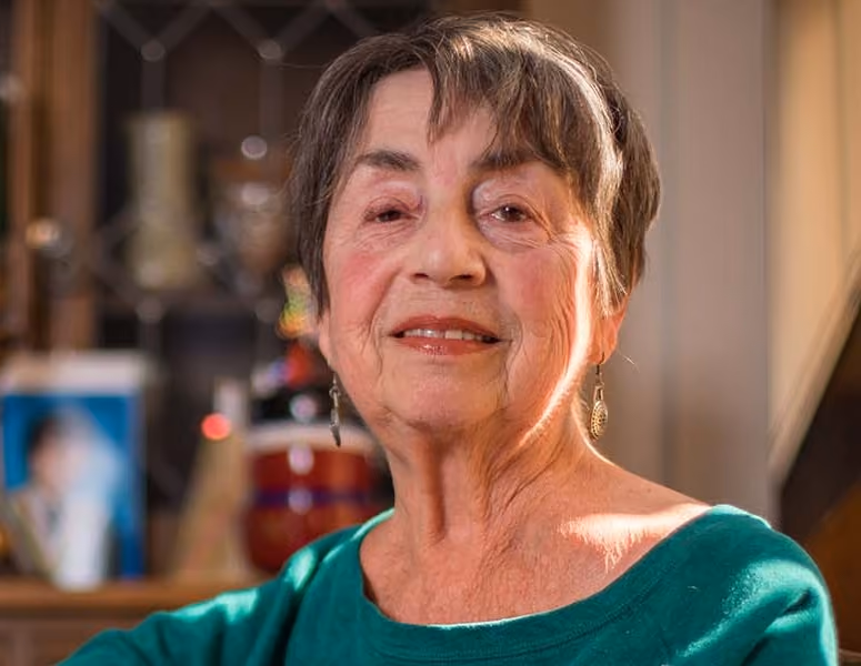Older woman with short hair smiling indoors.