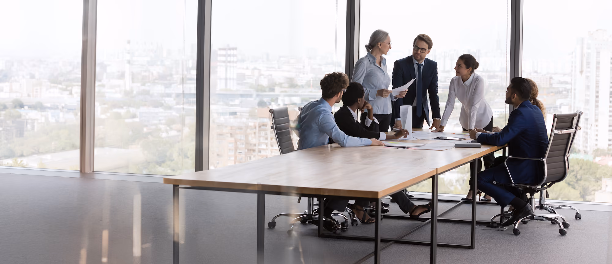 Group of people meeting around a boardroom table.