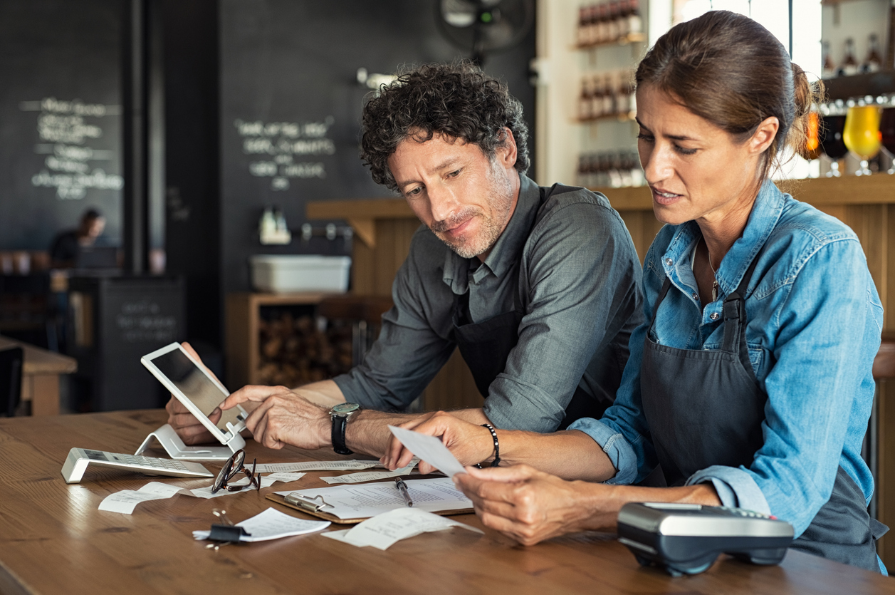 Two business owners review paperwork at a desk.