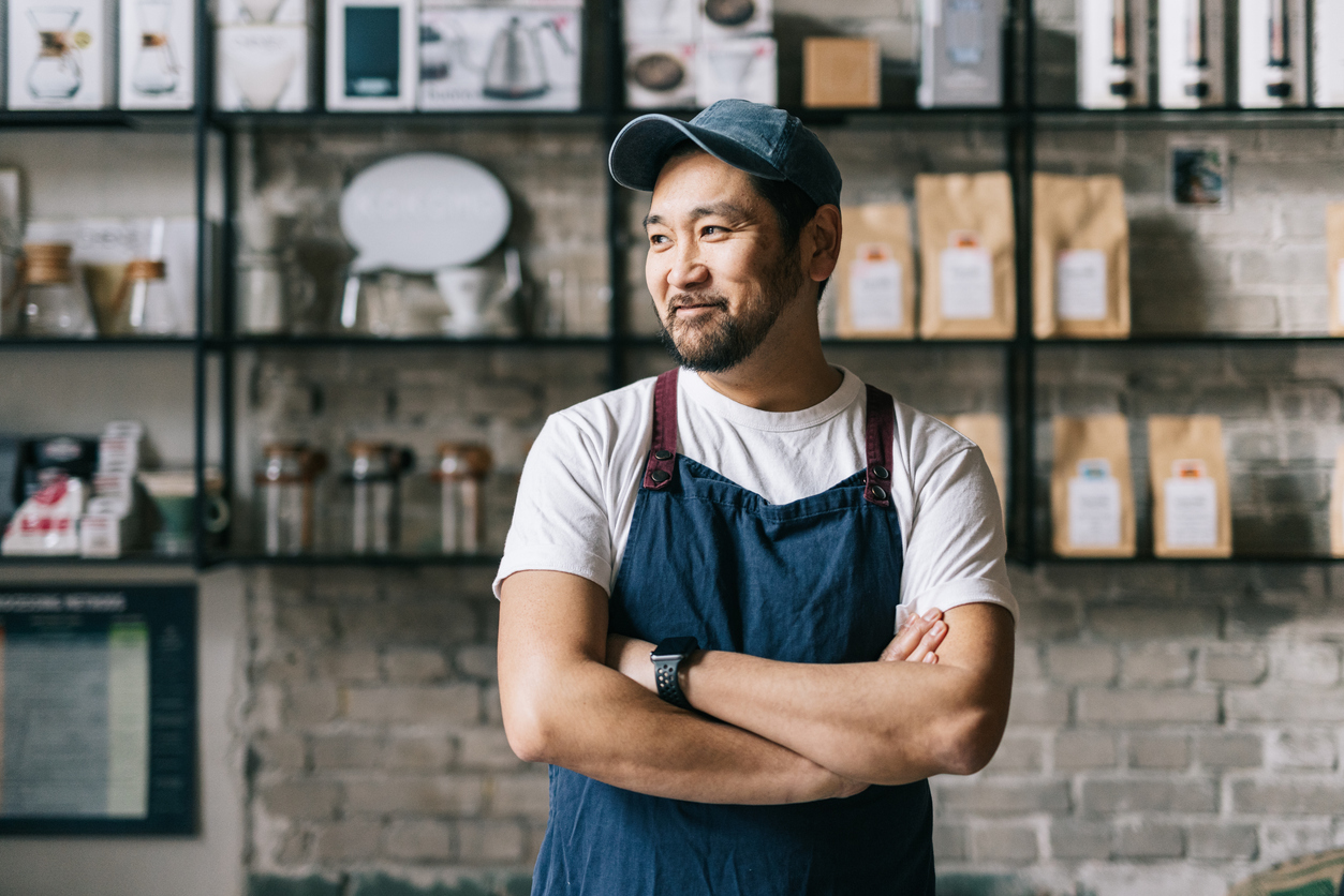 Small business owner in his shop smiling proudly.