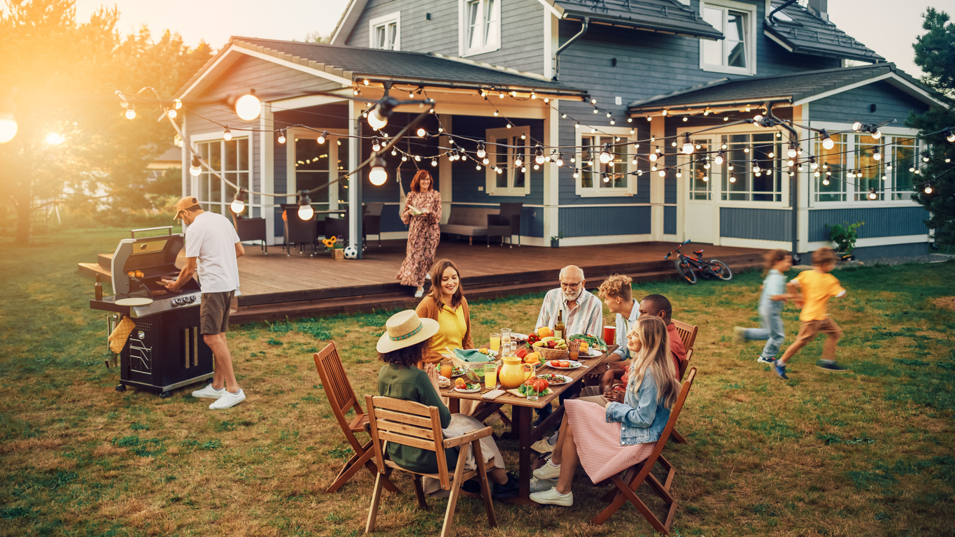 A multi-generational family enjoys an outdoor BBQ in their backyard.