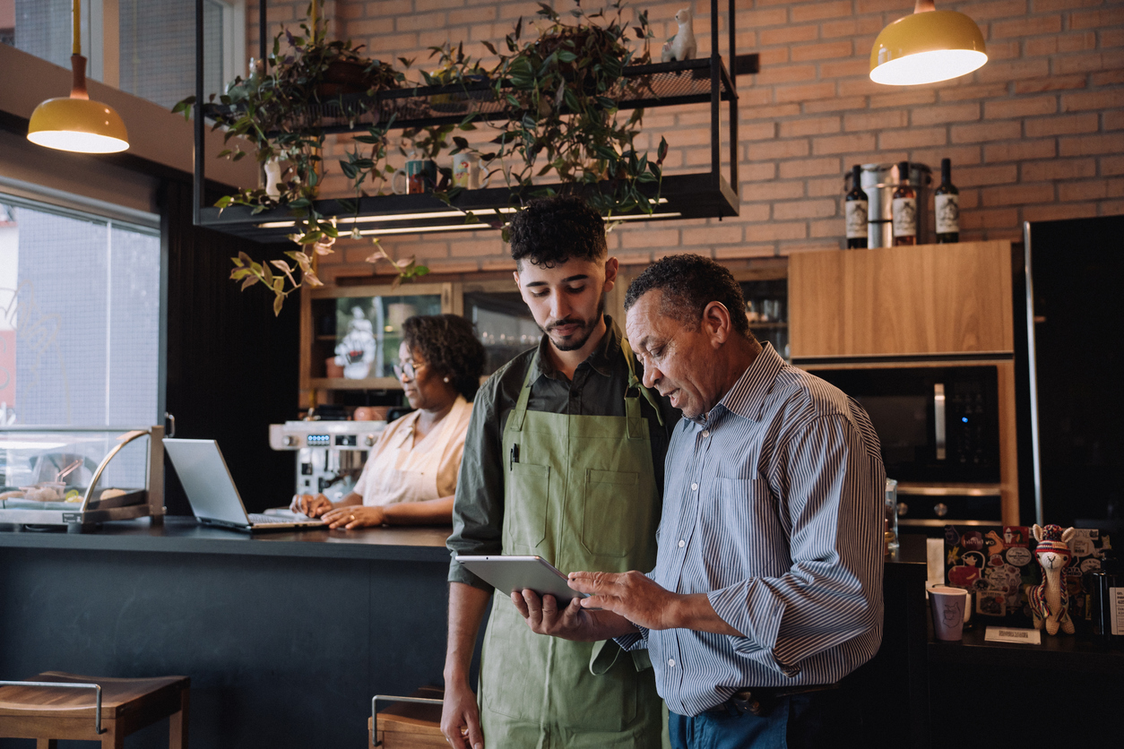 A small business owner looks over an iPad with one of his employees.