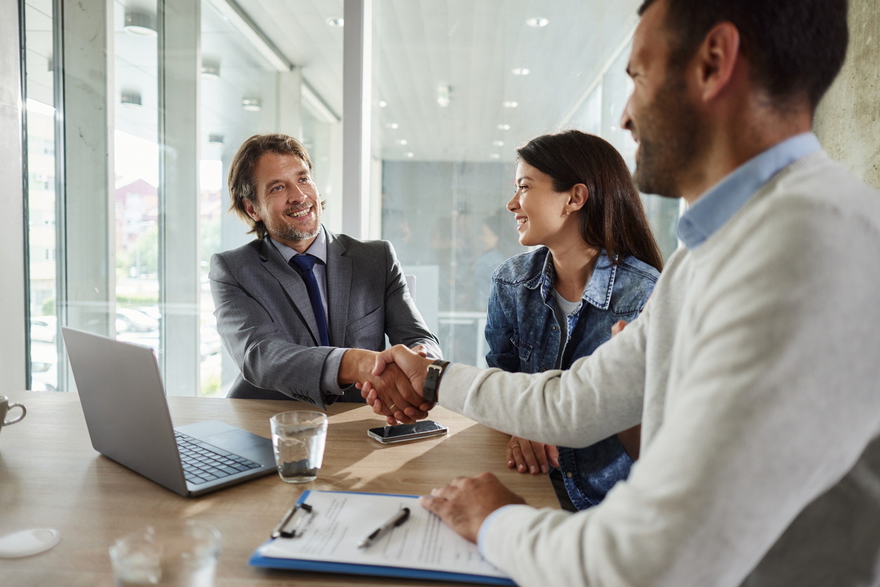 A loan lender shakes the hand of a borrower in his office.