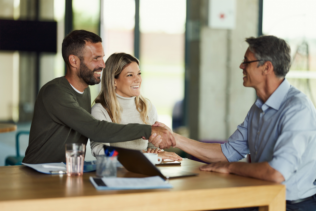 A couple getting a loan shake hands with their loan officer.