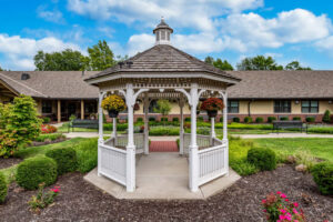 Gazebo surrounded by landscaped gardens at Morningside Place, a memory care community in Overland Park, KS, featuring colorful flowers and greenery.