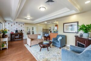 Cozy sitting area in Anthem Memory Care community, featuring two sofas, a coffee table, decorative plants, and warm lighting, located in Wichita, KS.