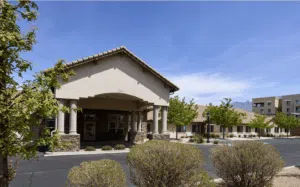 Memory care community building with welcoming entrance, landscaped surroundings, and clear blue sky, representing Anthem Memory Care's commitment to quality senior care.