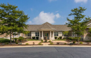 Exterior view of Franklin Place memory care community in Franklin, WI, featuring a welcoming entrance, landscaped surroundings, and a clear blue sky.