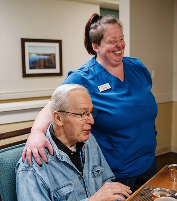 Senior man enjoying companionship with a smiling caregiver in a welcoming environment, highlighting person-centered care and emotional connection in memory support.