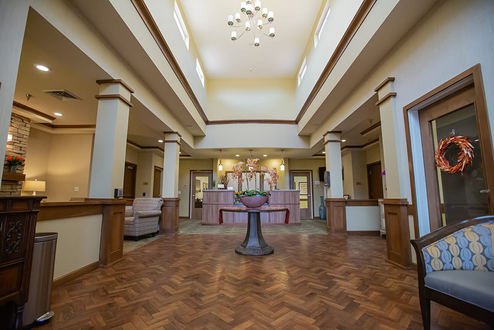 Interior view of Vineyard Place memory care community in Murrieta, CA, featuring a spacious lobby with decorative plants, a reception desk, and comfortable seating arrangements.