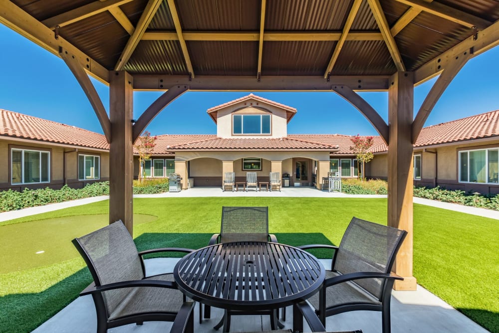 Outdoor sitting area with a gazebo and table, surrounded by landscaped grounds at Anthem Memory Care community in Murrieta, CA.