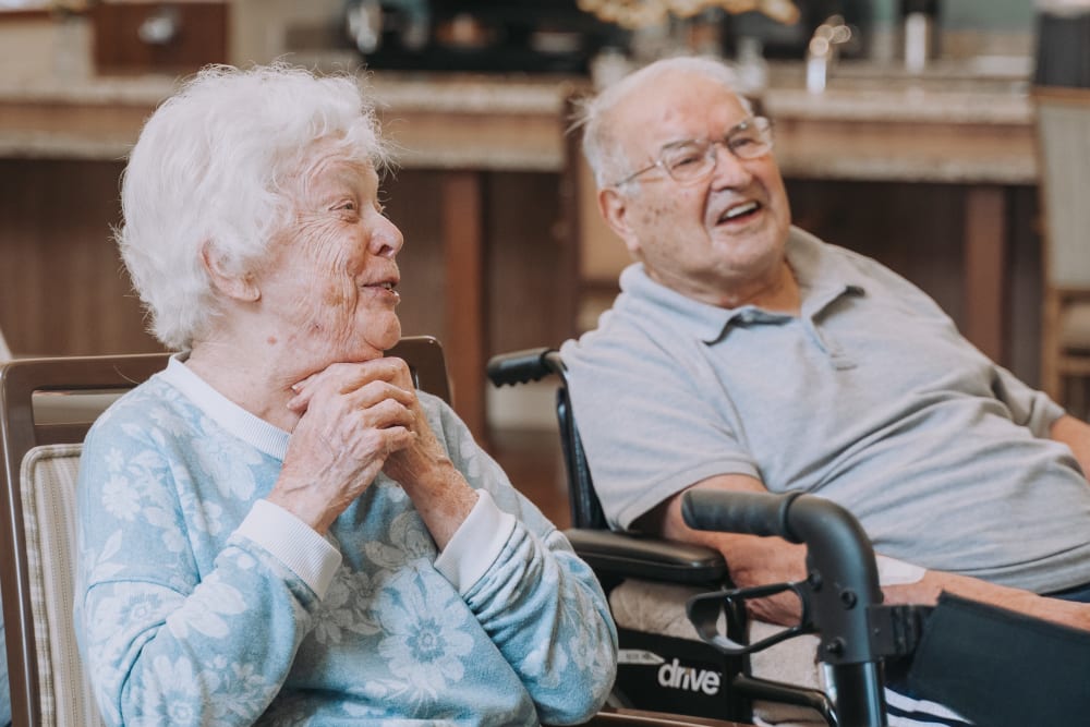 Elderly couple enjoying a moment together in a warm, inviting memory care environment, emphasizing person-centered care and emotional engagement.