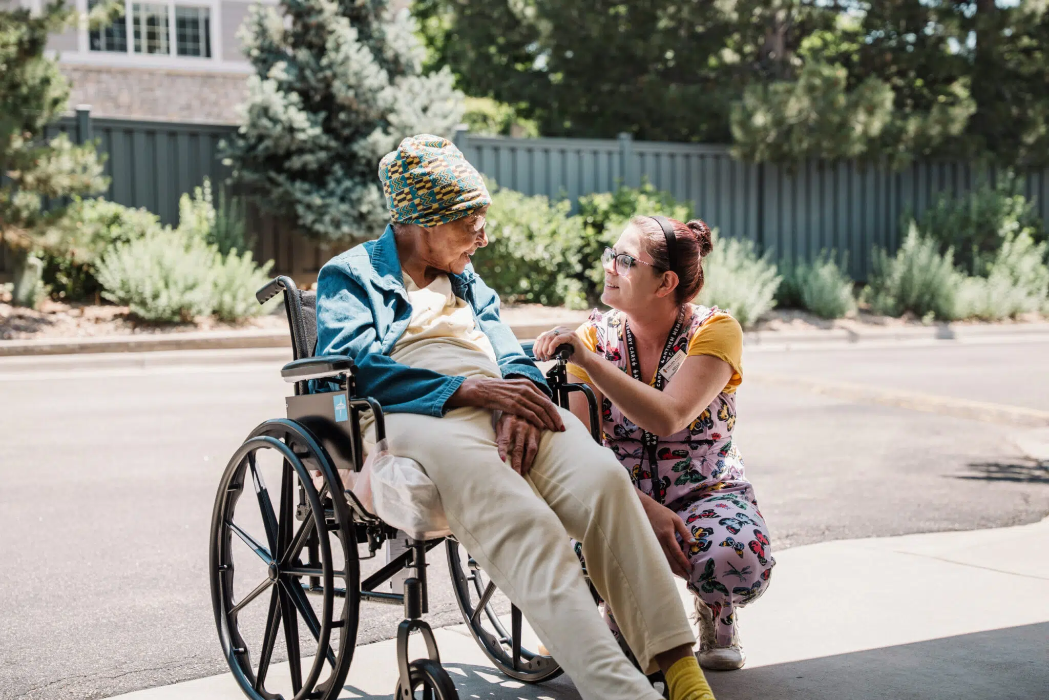 Chelsea Place staff member talking to a resident in a wheelchair outside
